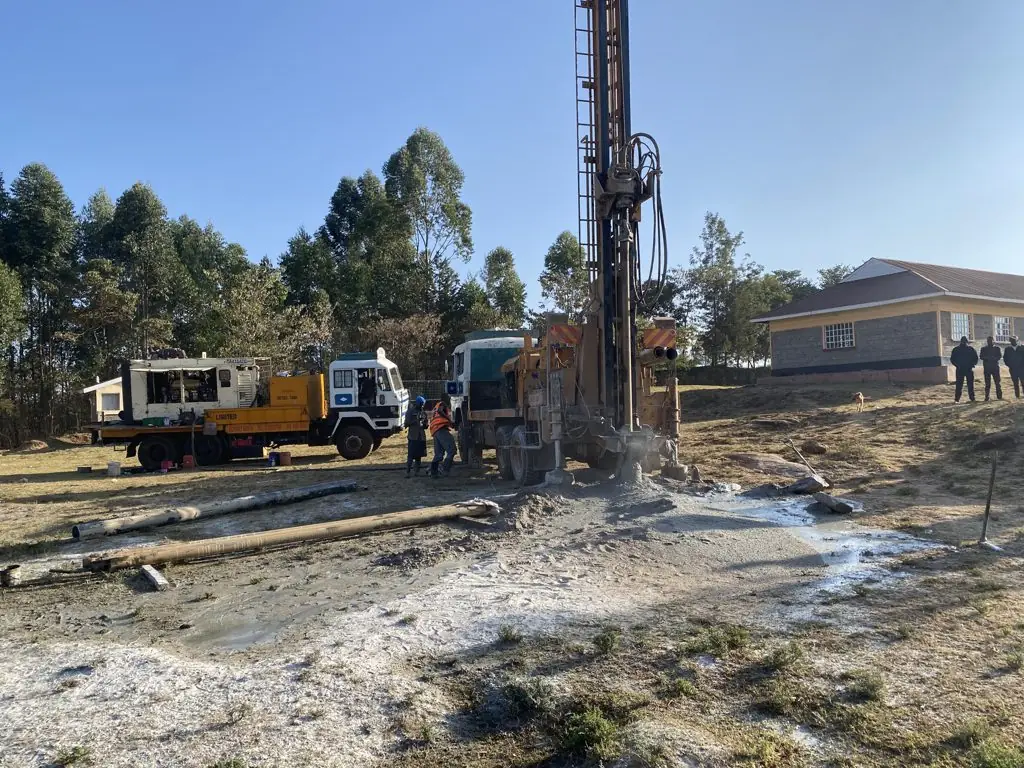 Drilling rig, compressor truck and crew beside Chepkongi Dispensary, Eldoret