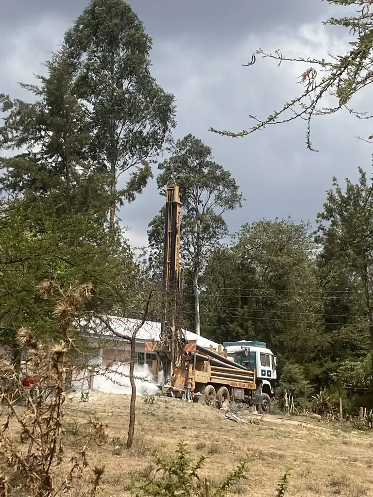 Drilling rig among tall trees beside Chepkongi Primary School, Eldoret