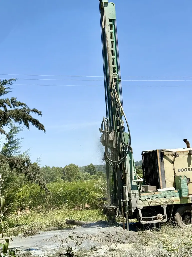 Rig drilling with spray rising from the borehole at Murgor School