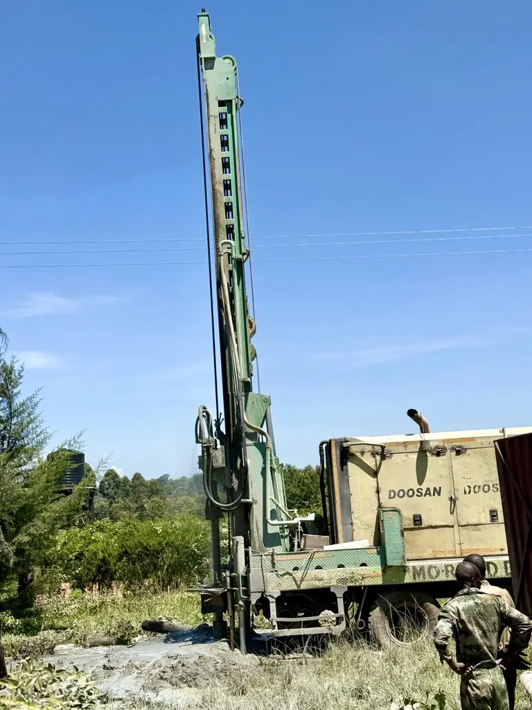Drilling rig and compressor truck with crew at Murgor School, Turbo